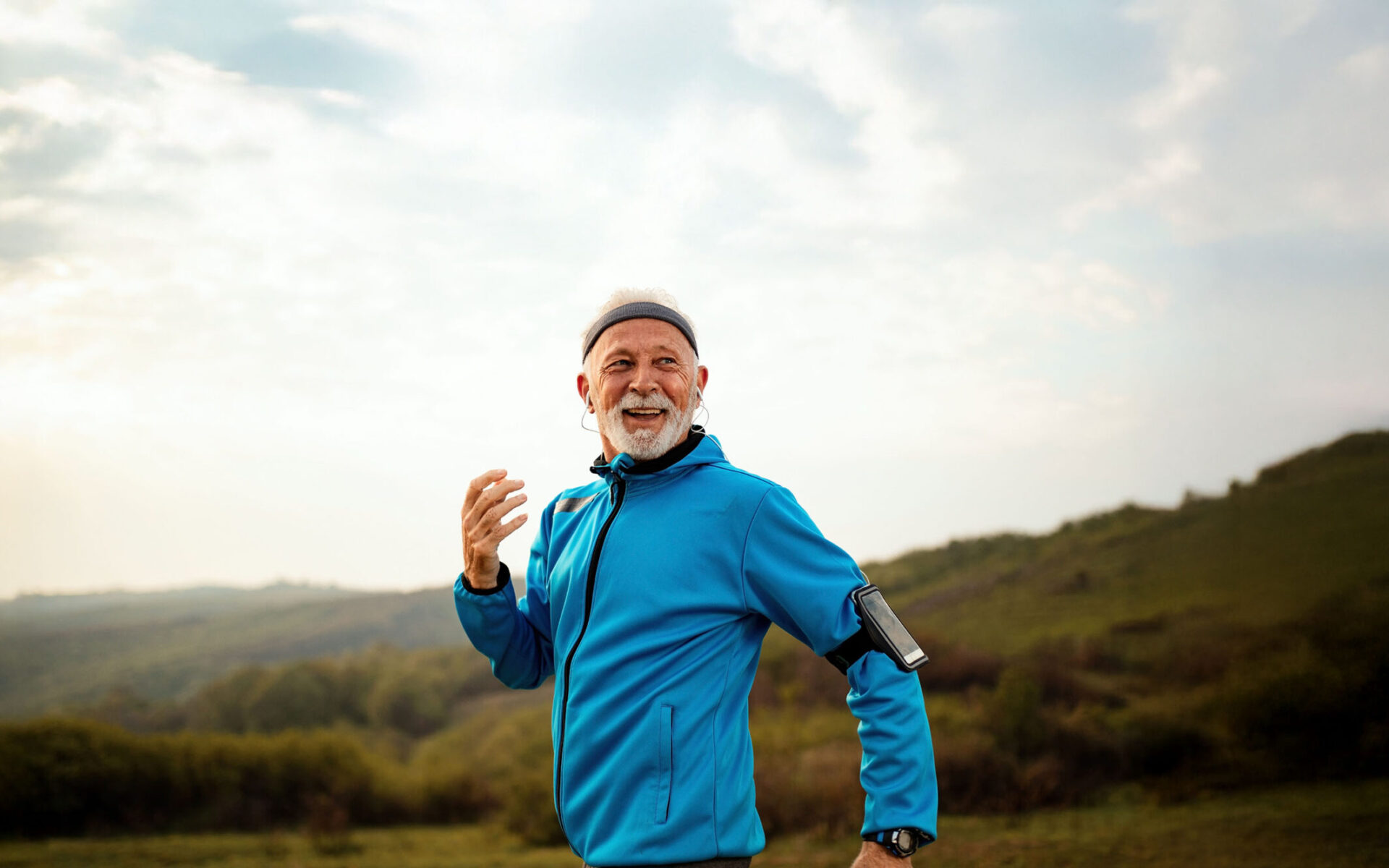Older man jogging through grassy hills
